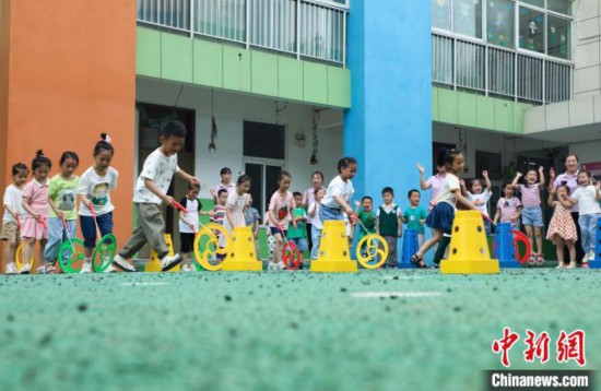 在肥西縣山南鎮中心幼兒園，孩子們在玩滾鐵環游戲。　陳家樂 攝