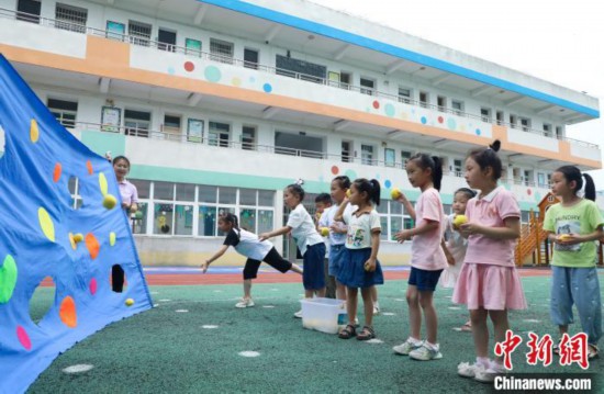 在肥西縣山南鎮中心幼兒園，孩子們在玩布洞投球游戲。　陳家樂 攝