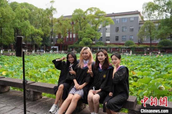 6月19日，時值一年畢業季，四川大學望江校區荷花池裡的荷花盛開，成為了畢業生們的打卡聖地，吸引了眾多畢業生拍照留念。圖為畢業生在荷花池邊拍照留念。中新社記者 安源 攝