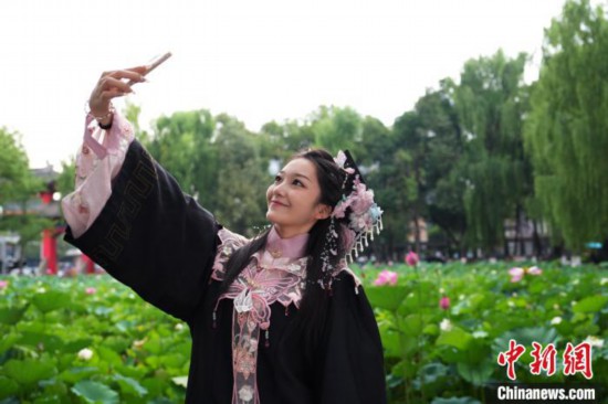 6月19日，時值一年畢業季，四川大學望江校區荷花池裡的荷花盛開，成為了畢業生們的打卡聖地，吸引了眾多畢業生拍照留念。圖為畢業生在荷花池邊拍照留念。中新社記者 安源 攝