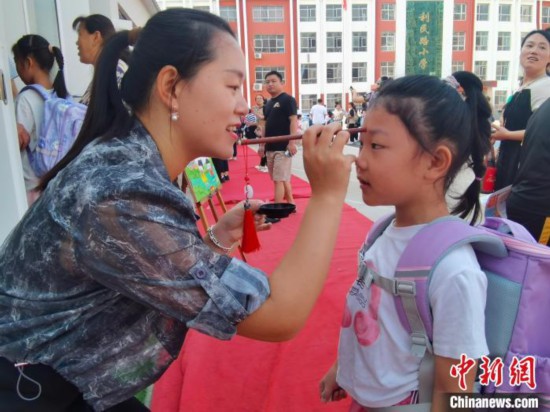 圖為衡水市利民路小學，老師為學生點朱砂痣，寓意開啟智慧。張鬆 攝